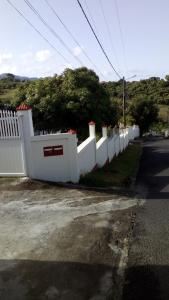 una cerca blanca al costado de una carretera en résidences aux saveurs des mangues, en Baillif