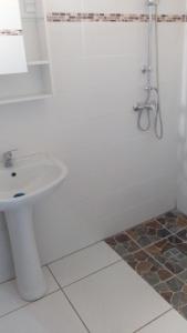 a white bathroom with a sink and a shower at résidences aux saveurs des mangues in Baillif