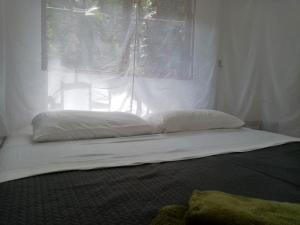 a bed with two pillows in front of a window at Casa Bolita in Dos Brazos