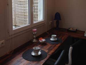 エイジーヌにあるWisteriaの窓際の木製テーブルの上にカップ2杯とソーサー