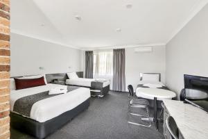 a hotel room with two beds and a television at Bushman's Motor Inn in Lithgow