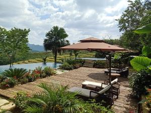a patio with an umbrella and chairs and a pool at Puluong Home in Pu Luong