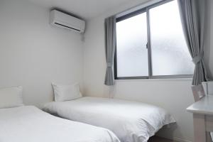 two beds in a room with a window at nestay inn tokyo senju in Tokyo