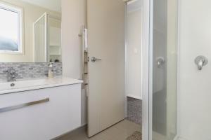 y baño blanco con lavabo y ducha. en Omokoroa Sea View Apartment, en Omokoroa