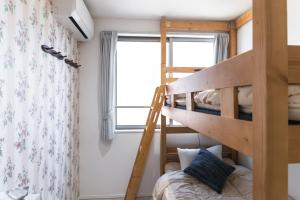 a bunk bed in a small room with a ladder at nestay inn tokyo senju in Tokyo