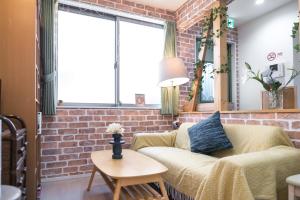 uma sala de estar com um sofá e uma parede de tijolos em nestay inn tokyo senju em Tóquio