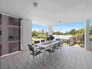 a dining room table with chairs and a window at Pacific Marina Apartments in Coffs Harbour