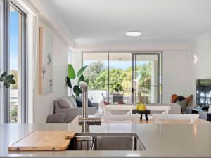 a kitchen with a sink and a living room at Pacific Marina Apartments in Coffs Harbour