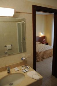 a bathroom with a sink and a mirror and a bed at Hotel Industria in Brescia
