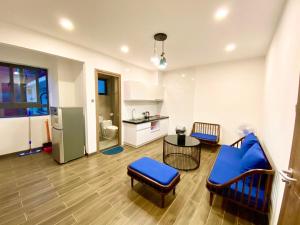 a living room with blue chairs and a kitchen at Kim Oanh Apartment in Da Lat