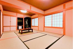 an empty room with a table in a room with windows at Minshuku Asogen in Aso