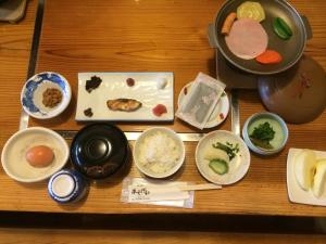 a table topped with bowls and plates of food at Minshuku Asogen in Aso