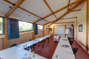 a classroom with long tables and chairs and a whiteboard at Hotel Le Phoebus Garden & Spa in Gruissan