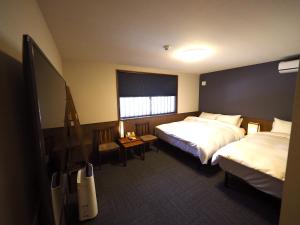 Habitación de hotel con 2 camas y TV de pantalla plana. en Hotel Sou Kyoto Gion en Kyoto