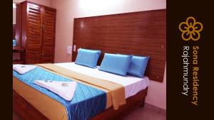 拉賈蒙德里的住宿－Sona Residency，一间卧室配有一张带蓝色枕头的床
