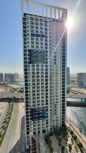 a tall building with the sun shining on it at Blue Ocean Holiday Homes - Prive in Dubai