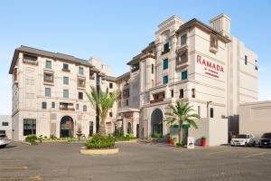 a large white building with palm trees in a parking lot at Ramada by Wyndham Lahore Gulberg II in Lahore