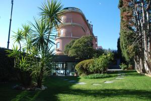 un edificio rosa con palme di fronte di Hotel Santa Maria a Chiavari