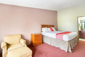 a bedroom with a bed and a chair at OYO Hotel Daleville AL Hwy 84 in Daleville