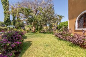 a yard with purple flowers and a building at JoysVilla Family Holiday Home in Malindi