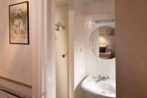 a bathroom with a sink, mirror and a painting on the wall at Hôtel du Levant in Paris