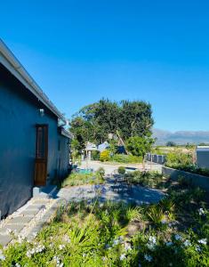 a house with a blue wall and a garden at Bonne Chance Cottage in Paarl