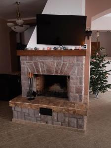 TV en la parte superior de una chimenea de ladrillo con un árbol de Navidad en Villa Atriolum, en Băile Tuşnad