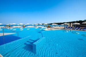 ein großer blauer Swimmingpool mit Liegestühlen und Sonnenschirmen in der Unterkunft Apartments Amfora Plava Laguna in Umag