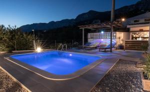 a swimming pool in the middle of a backyard at night at Villa Mia Stella in Podgora