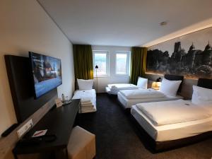 a hotel room with two beds and a flat screen tv at Euro Hotel Wertheim in Wertheim