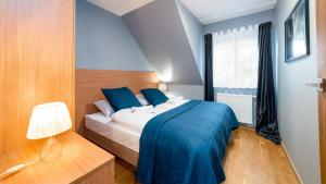 Schlafzimmer mit einem Bett mit blauer Bettwäsche und einem Fenster in der Unterkunft Apartamenty Sun & Snow Komuny Paryskiej in Karpacz