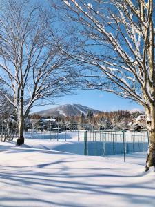 un parque cubierto de nieve con árboles y una valla en Appi Life is Beautiful, en Hachimantai