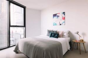 ein weißes Schlafzimmer mit einem Bett und einem Fenster in der Unterkunft 2 BR Modern Melbourne CBD Apartment in Melbourne