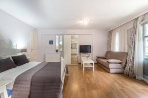 Un dormitorio con una cama, un sofá y un televisor. en UrbanStay, en Atenas