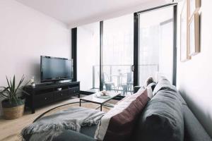 ein Wohnzimmer mit einem Sofa und einem TV in der Unterkunft 2 BR Modern Melbourne CBD Apartment in Melbourne