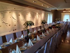 Un salón de banquetes con mesas y sillas blancas y flores. en Markus, en Kolonowskie