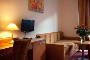 a room with a couch and a desk with a television at Hotel Orion Berlin in Berlin
