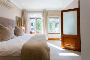 um quarto com uma cama grande e uma janela em Koetsiershuis em Stellenbosch