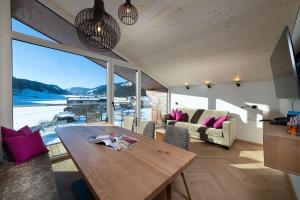 a living room with a wooden table and a large window at Harmls Aparthotel in Flachau