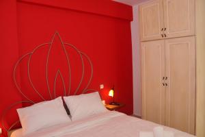 Un dormitorio con una pared roja y una cama en Dominique Rooms Meteora, en Kalambaka