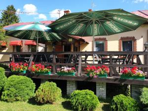 um pátio com flores e guarda-sóis em frente a um restaurante em Gościniec LECH em Kosewo