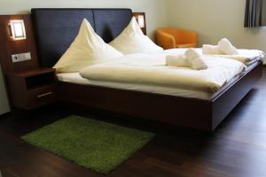 a large bed with white sheets and a green rug at Hotel Brantl in Roding