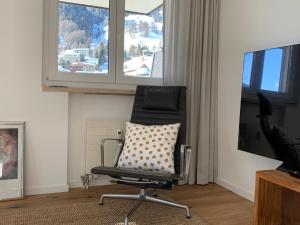 einen Stuhl mit einem Kissen vor einem Fernseher in der Unterkunft Ferienwohnung Parsennblick mit Dachterrasse in Davos