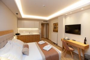 Dormitorio con cama, escritorio y TV en No21 Luxury Suites, en Tesalónica