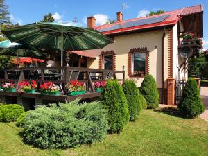 a house with a table with an umbrella and some plants at Gościniec LECH in Kosewo
