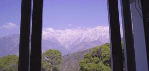 a view of a snowy mountain range from a window at Hotel Saheb's Castle McLeodganj in McLeod Ganj