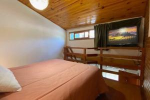 a bedroom with a bed and a flat screen tv at Casa en los troncos Parque Primavesi. in Mar del Plata