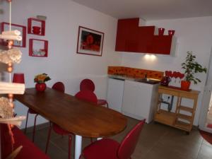 cocina con mesa de madera y sillas rojas en Chambres d'hôtes Les Coquelicots, en Marieulles