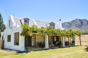 a white house with trees and mountains in the background at Raptor Rise Farm in Tulbagh