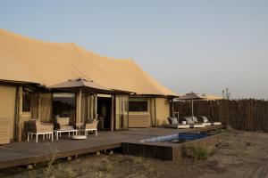 a luxury tent with a deck with chairs and umbrellas at Kingfisher Retreat by Sharjah Collection in Kalbā